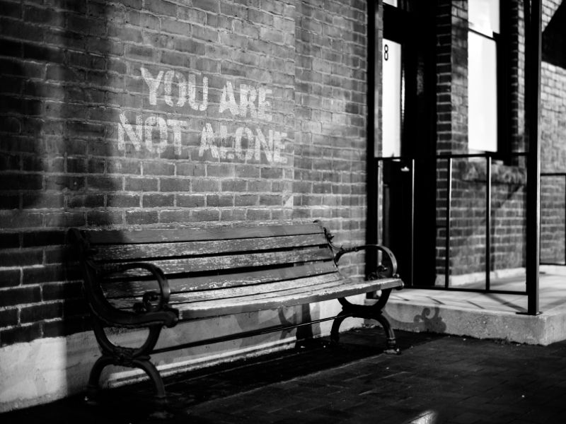 Empty city bench with the message "You are not alone," symbolizing support and encouragement for men struggling with emotional silence.