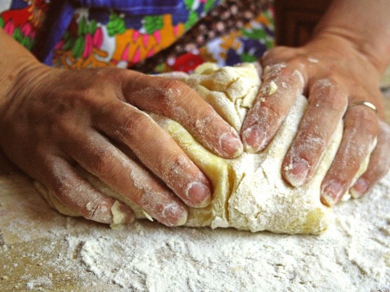 Woman kneading dough; an activity helping homemakers to live on a budget.