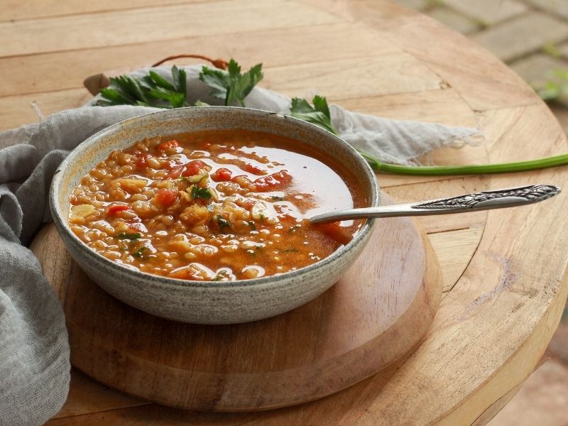 A bowl of hearty red lentil soup garnished with fresh herbs, perfect for simple winter food ideas to warm up during cold days.