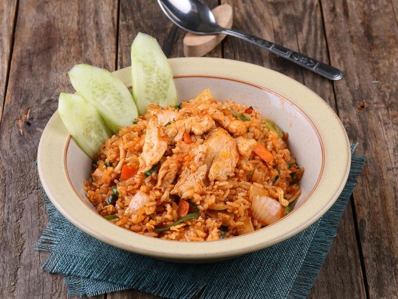 A bowl of flavorful chicken fried rice garnished with cucumber slices, illustrating simple winter food idea for a comforting meal.