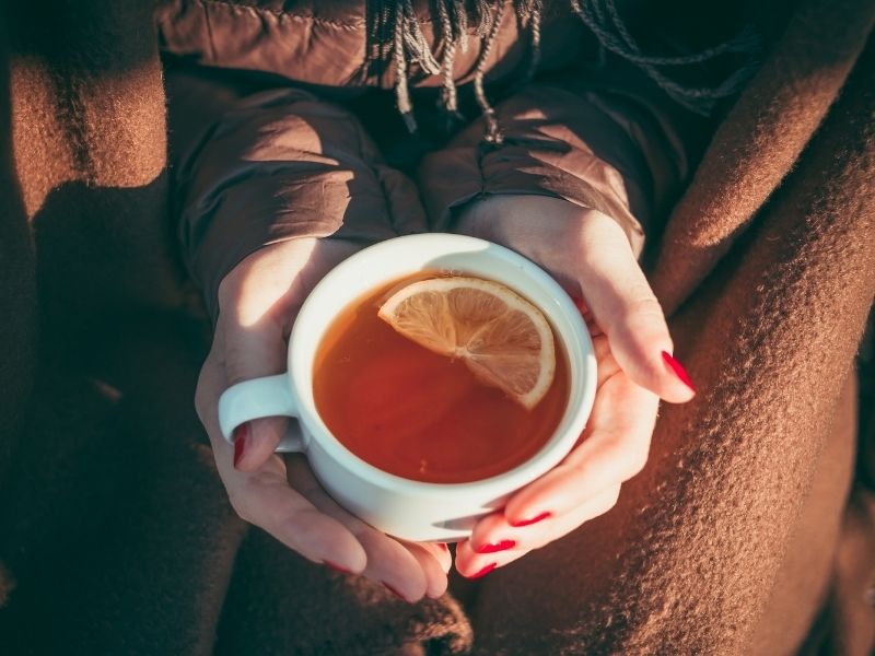 A person holding a mug of hot tea, embodying the cozy atmosphere of simple winter food ideas.