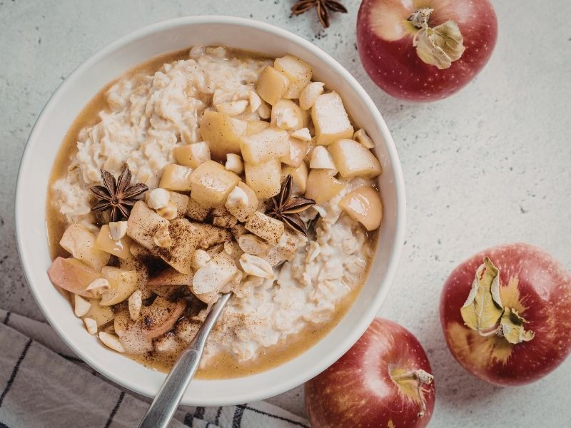 A bowl of warm oatmeal topped with chopped apples, nuts, and spices, illustrating simple winter food ideas for a cozy and healthy winter breakfast.