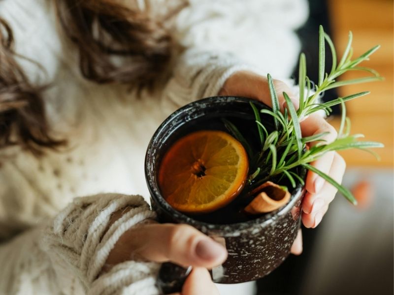 Person holding a mug with herbal tea, representing a warm winter self-care ritual.