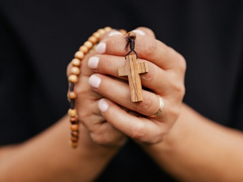 Woman gently holding a Rosary, reflecting devotion and humility in Catholic practice.
